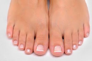 Beautiful well-groomed female feet with the French pedicure Beautiful well-groomed female feet with the French pedicure